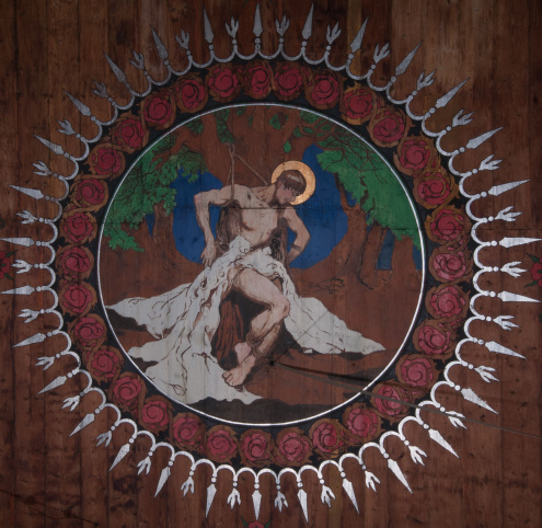Zdjęcie stropu kościoła św. Sebastiana w Wieliczce, przedstawiające fragment polichromii z medalionem z wizerunkiem św. Sebastiana przywiązanego do drzewa i przebitego strzałami.