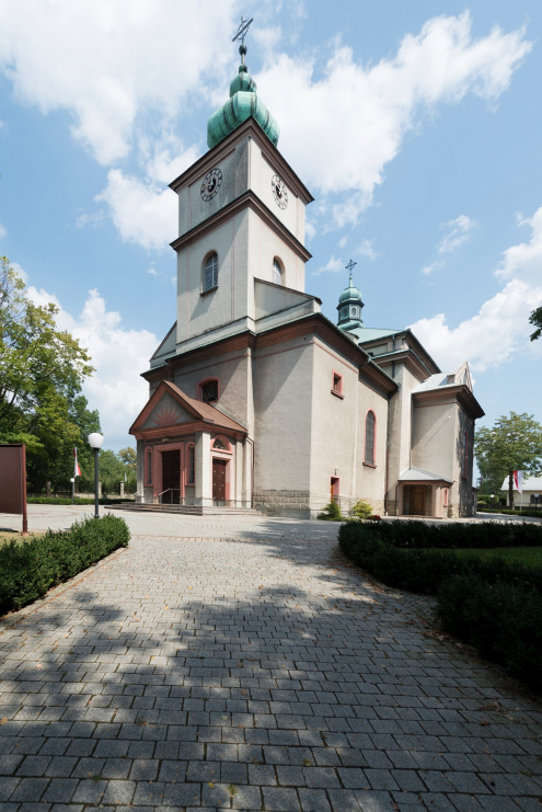 Zdjęcie kościoła w Czańcu pod strony  południowo-zachodniej drogi. Na tle pogodnego nieba widoczna część z wieżą zwieńczoną hełmem i przedsionkiem.