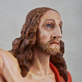 Fragment rzeźby Chrystusa, przedstawiający jego głowę z rozwianymi włosami i ramiona.