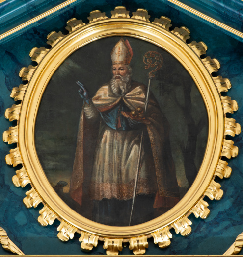 Obraz ołtarzowy z wizerunkiem św. Mikołaja, ukazanego do kolan, w stroju biskupim. Prawą ręką błogosławi, lewą przytrzymuje pastorał i podtrzymuje księgę z trzema kulami. Scena na tle pejzażu.