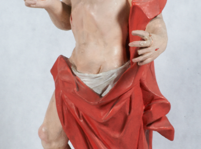 Rzeźba Chrystusa Zmartwychwstałego, ubranego w czerwony płaszcz, który prawą nogę opiera na czaszce. Z jego głowy wychodzą trzy wiązki promieni.