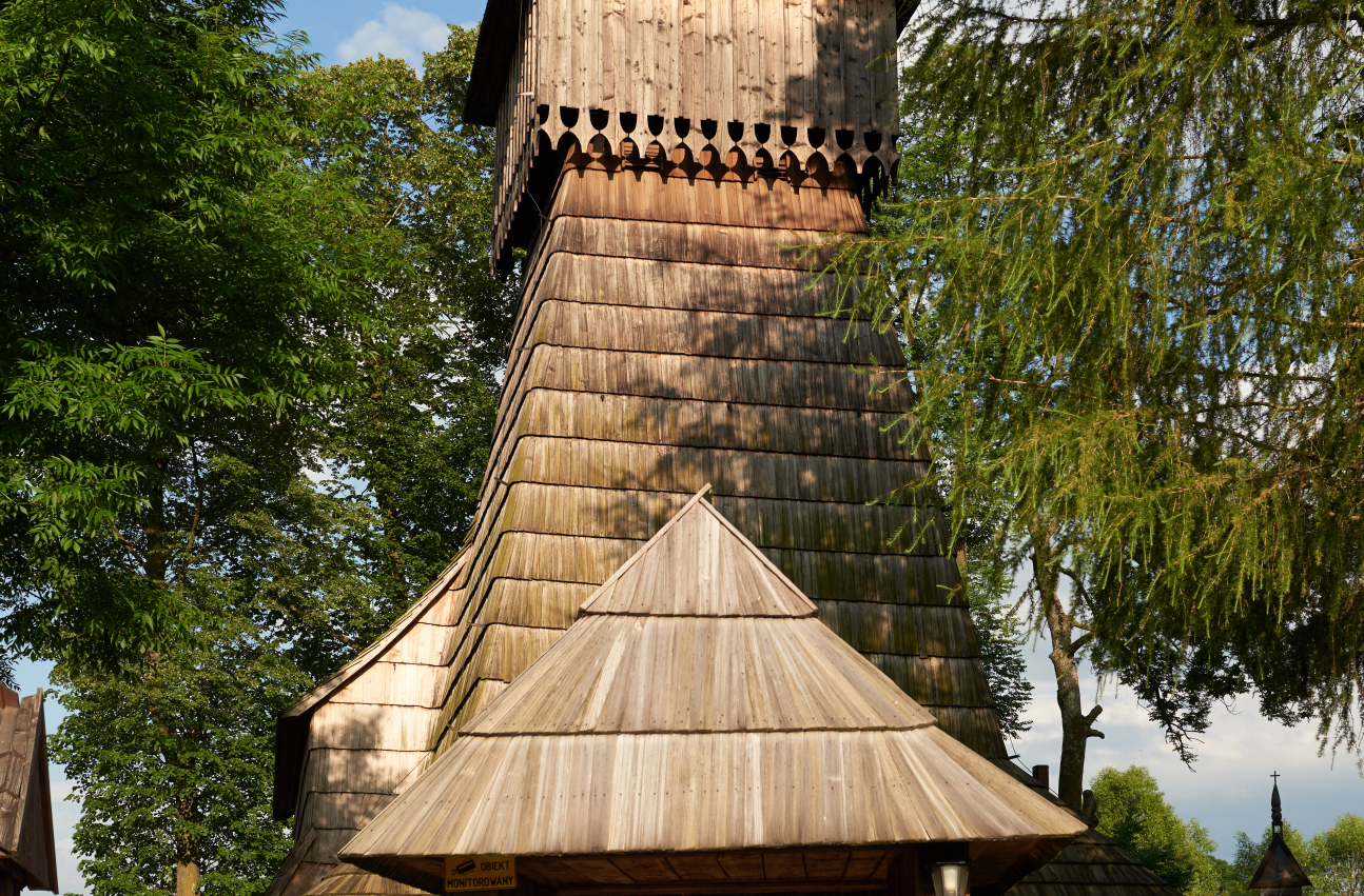 Zdjęcie 4. Architektura kościoła w Dębnie Podhalańskim. Widoczna wieża i drewniana bramka wejściowa na teren przykościelny.