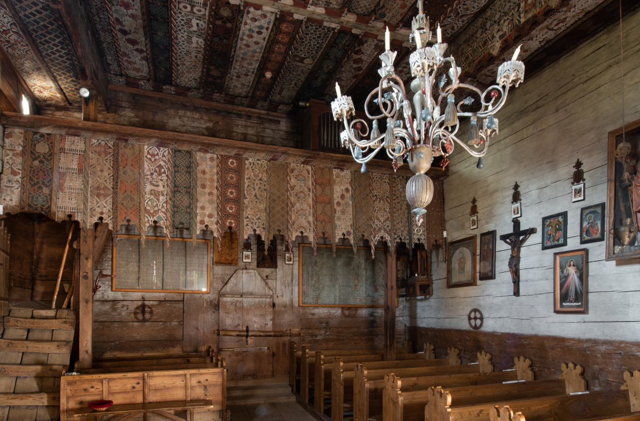 Zdjęcie 7. Wnętrze kościoła w Dębnie Podhalańskim. Na pierwszym planie dwa rzędy ławek, u góry polichromowany strop.