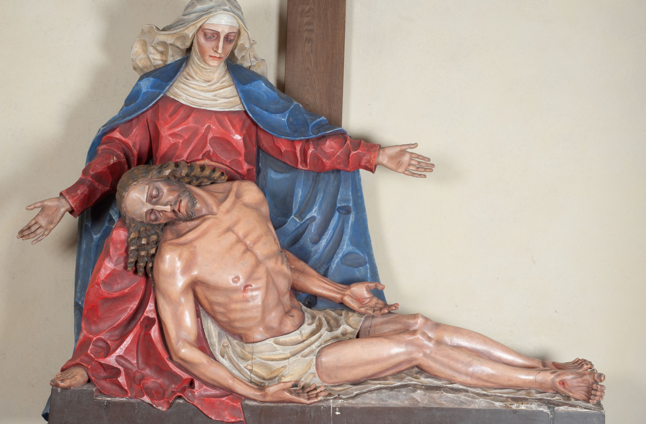 Fragment grupy rzeźbiarskiej „Pieta” w kościele w Kamieniu. Matka Boska siedzi pod krzyżem z rozłożonymi na boki rękami, na jej kolanach leży martwe ciało Jezusa.