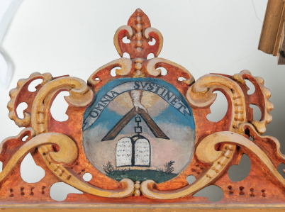 Drugi emblemat na szafie zakrystyjnej przedstawia wyłaniającą się z chmur rękę, która trzyma w dłoni węgielnicę i przymocowany do niej Dekalog na łańcuszku. Emblemat został opatrzony napisem „Omnia sustinet”.