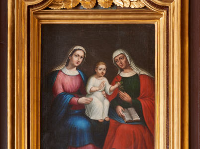 Obraz ołtarzowy z przedstawieniem siedzących obok siebie Marii i św. Anny, pomiędzy którymi siedzi Dzieciątko trzymane przez matkę. Jezus podaje babce kiść winogron.