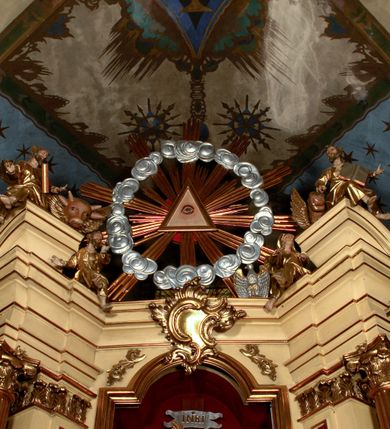 Zdjęcie nr 2: Przyścienny architektoniczny ołtarz jednoosiowy i jednokondygnacjowy, ze zwieńczeniem. Ołtarz jest murowany, w formie prostopadłościennej, skrzyni z portatylem i drewnianym antepedium. Nastawa ołtarzowa jest osadzona na dwóch flankujących mensę wysokich, ukośnych cokołach. Część środkową retabulum ujmuje para skośnie ustawionych filarów, pilastrów i kolumn o korynckich kapitelach wspierających subtelnie wyłamujące się ponad nimi, przerwane w partii architrawu i fryzu belkowanie. Zwieńczenie jest w formie przerwanego, półkolistego skośnie ustawionego przyczółka. Boki cokołu retabulum zdobi motyw wazonów. Pole ujętego profilowaną, złoconą ramą antepedium wypełniają trzy okrągłe medaliony, środkowy z monogramem imienia Jezus, w dwóch bocznych litery A i Ω, a w narożach motywy akantu. Część środkowa retabulum jest zaaranżowana w formie wnęki w kształcie stojącego prostokąta zamkniętego nadwieszonym łukiem półkolistym, ujętej profilowaną, złocona ramą, której dłuższe boki zdobią różane gałązki z kwiatami. Pośrodku belkowania znajduje się fantazyjny, rocaille'owy kartusz. Boki zwieńczenia zdobią figury czterech ewangelistów wraz z ich symbolami od prawej: św. Marek z lwem, św. Jan z orłem, św. Mateusz (brak), św. Łukasz z wołem. Pośrodku zwieńczenia znajduje się promienista gloria o alternowanych promieniach, z wieńcem srebrzonych obłoków oraz z trójkątem z okiem Opatrzności Bożej w centrum. Po bokach retabulum umieszczono figury św. Wojciecha po prawej i św. Stanisława po lewej stronie. 
Tabernakulum jest w formie niewielkiej, prostopadłościennej skrzynki obitej miedzianą blachą z trybowanym chryzmonem na drzwiczkach i mniejszymi scenami figuralnymi w obramowaniu.

 Struktura ołtarza utrzymana jest w kolorze kremowym, detal architektoniczny i ornamentyka są złocone.   

