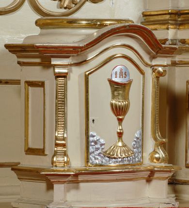 Zdjęcie nr 5: Ołtarz przyścienny, narożny, usytuowany po prawej stronie, w pierwszym od prezbiterium przęśle nawy, przy ścianie tęczowej. Architektoniczny, jednokondygnacyjny ze zwieńczeniem. Mensa murowana, prostopadłościenna, w typie skrzyniowym, z relikwiami nieznanego z imienia jednego ze świętych męczenników. Antepedium z blachy w drewnianej ramie, z monogramem imienia Jezus w centrum. Niewielkie, drewniane tabernakulum architektoniczne, na cokole. Jednoskrzydłowe drzwiczki zdobione płaskorzeźbionym kielichem z hostią, flankowane pilastrami o trzonach spływających wolutowo, podtrzymujących wyłamany gzyms. Nastawa ołtarzowa wsparta na flankujących mensę wysokich, dwudzielnych postumentach, dekorowanych złoconymi płycinami zdobionymi rocaille'em. Części boczne na całej wysokości ustawione ukośnie w stosunku do osi środkowej ołtarza. Wysunięte przed zdwojone pilastry z trzonami dekorowanymi rocaille'ami, kolumny o kanelowanych na całej wysokości, złoconych trzonach i kompozytowych kapitelach, dźwigają bogato profilowane, gierowane, pełne belkowanie, wyłamane na osi podpór. Wieńczy je przerwany, półkolisty przyczółek. W polu nastawy złocona, profilowana rama o kształcie stojącego, podciętego półkoliście u podstawy prostokąta zamkniętego łukiem wklęsło-wypukłym z uskokiem. Poniżej i powyżej złocone aplikacje w formie mocno przestylizowanych liści akantu i muszli palmetowych. Wewnątrz wysuwane dwa obrazy: z Matką Boską Różańcową w sukience i ze św. Anną (obecnie niedostępny – popsuty mechanizm wysuwający). Na belkowaniu osadzony rocaille'owy kartusz. Zwieńczenie o wykrojonych wolutowo bokach zamknięte łukiem wklęsło-wypukłym, utworzonym przez dwie przeciwstawne woluty. U szczytu złocona, ażurowo wycinana muszla palmetowa. W polu zwieńczenia obraz na płótnie ze św. Józefem i Dzieciątkiem w kształcie stojącego prostokąta o ściętych krawędziach dolnych i wklęsłych bokach, zamkniętego łukiem wklęsło-wypukłym z uskokiem. Flankują go dwie niewielkie aplikacje rocaille'owe. Na tylne postumenty cokołu spływają woluty, lewa z monogramem maryjnym. 
Ołtarz obecnie przemalowany na kremowo. Ornamenty, załamania profili, ramy, trzony kolumn są złocone.