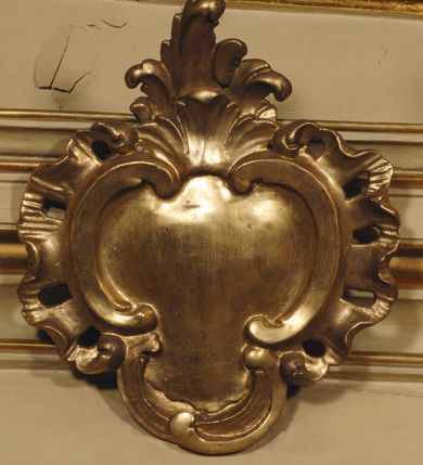 Zdjęcie nr 22: Ołtarz przyścienny, narożny, usytuowany po lewej stronie, w pierwszym od prezbiterium przęśle nawy, przy ścianie tęczowej. Architektoniczny, jednokondygnacyjny ze zwieńczeniem. Mensa murowana, prostopadłościenna, w typie skrzyniowym, z relikwiami nieznanego z imienia świętego męczennika. Antepedium z blachy w drewnianej ramie, z monogramem maryjnym w centrum. Niewielkie, drewniane tabernakulum jednodrzwiowe; lekko wypukłe drzwiczki zdobione płaskorzeźbionym kielichem z hostią wkomponowanym w złoconą płycinę zamkniętą łukiem nadwieszonym. Boki tabernakulum ujęte wolutowymi esownicami ustawionymi ukośnie w stosunku do jego lica. Zwieńczenie w formie przeciwstawnych wolut zdobionych rocaille'em. Nastawa ołtarzowa wsparta na flankujących mensę wysokich, dwudzielnych postumentach dekorowanych złoconymi płycinami zdobionymi rocaille'em. Części boczne na całej wysokości ustawione ukośnie w stosunku do osi środkowej ołtarza. Wysunięte przed zdwojone pilastry z trzonami dekorowanymi rocaille'ami, kolumny o kanelowanych na całej wysokości, złoconych trzonach i kompozytowych kapitelach, dźwigają bogato profilowane, gierowane, pełne belkowanie, wyłamane na osi podpór. Wieńczy je przerwany, półkolisty przyczółek. W polu nastawy złocona, profilowana rama o kształcie stojącego prostokąta zamkniętego łukiem wklęsło-wypukłym z uskokiem. Na jej boku, z prawej strony nałożona złocona aplikacja kwiatowa. Wewnątrz wysuwane dwa obrazy: z Matką Boską Niepokalanie Poczętą i Aniołem Stróżem (obecnie wyjęty) pędzla Wojciecha Eljasza-Radzikowskiego. Na belkowaniu osadzony rocaille'owy kartusz. Zwieńczenie o wykrojonych wolutowo bokach zamknięte łukiem wklęsło-wypukłym utworzonym przez dwie przeciwstawne woluty. U szczytu złocona, ażurowo wycinana, muszla palmetowa. W polu obraz na blasze ze św. Antonim Padewskim i Dzieciątkiem Jezus w kształcie stojącego prostokąta o ściętych krawędziach dolnych i wklęsłych bokach, zamkniętego łukiem wklęsło-wypukłym z uskokiem. Flankują go dwie, niewielkie aplikacje rocaille'owe. Na tylnych postumentach cokołu dwie dużych rozmiarów, pełnoplastyczne rzeźby aniołów. Postaci stojące w silnym kontrapoście, o tanecznych, dynamicznych pozach. Ciała muskularne, odziane w bogate, złocone, mocno fałdowane szaty. Skrzydła złocone, karnacje polichromowane. Po obu bokach ołtarza niewielkie uszy utworzone z rocaille'ów. Ołtarz obecnie przemalowany na kremowo. Ornamenty, załamania profili, ramy, trzony kolumn złocone.