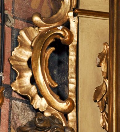 Zdjęcie nr 23: Ołtarz przyścienny, narożny, usytuowany po lewej stronie, w pierwszym od prezbiterium przęśle nawy, przy ścianie tęczowej. Architektoniczny, jednokondygnacyjny ze zwieńczeniem. Mensa murowana, prostopadłościenna, w typie skrzyniowym, z relikwiami nieznanego z imienia świętego męczennika. Antepedium z blachy w drewnianej ramie, z monogramem maryjnym w centrum. Niewielkie, drewniane tabernakulum jednodrzwiowe; lekko wypukłe drzwiczki zdobione płaskorzeźbionym kielichem z hostią wkomponowanym w złoconą płycinę zamkniętą łukiem nadwieszonym. Boki tabernakulum ujęte wolutowymi esownicami ustawionymi ukośnie w stosunku do jego lica. Zwieńczenie w formie przeciwstawnych wolut zdobionych rocaille'em. Nastawa ołtarzowa wsparta na flankujących mensę wysokich, dwudzielnych postumentach dekorowanych złoconymi płycinami zdobionymi rocaille'em. Części boczne na całej wysokości ustawione ukośnie w stosunku do osi środkowej ołtarza. Wysunięte przed zdwojone pilastry z trzonami dekorowanymi rocaille'ami, kolumny o kanelowanych na całej wysokości, złoconych trzonach i kompozytowych kapitelach, dźwigają bogato profilowane, gierowane, pełne belkowanie, wyłamane na osi podpór. Wieńczy je przerwany, półkolisty przyczółek. W polu nastawy złocona, profilowana rama o kształcie stojącego prostokąta zamkniętego łukiem wklęsło-wypukłym z uskokiem. Na jej boku, z prawej strony nałożona złocona aplikacja kwiatowa. Wewnątrz wysuwane dwa obrazy: z Matką Boską Niepokalanie Poczętą i Aniołem Stróżem (obecnie wyjęty) pędzla Wojciecha Eljasza-Radzikowskiego. Na belkowaniu osadzony rocaille'owy kartusz. Zwieńczenie o wykrojonych wolutowo bokach zamknięte łukiem wklęsło-wypukłym utworzonym przez dwie przeciwstawne woluty. U szczytu złocona, ażurowo wycinana, muszla palmetowa. W polu obraz na blasze ze św. Antonim Padewskim i Dzieciątkiem Jezus w kształcie stojącego prostokąta o ściętych krawędziach dolnych i wklęsłych bokach, zamkniętego łukiem wklęsło-wypukłym z uskokiem. Flankują go dwie, niewielkie aplikacje rocaille'owe. Na tylnych postumentach cokołu dwie dużych rozmiarów, pełnoplastyczne rzeźby aniołów. Postaci stojące w silnym kontrapoście, o tanecznych, dynamicznych pozach. Ciała muskularne, odziane w bogate, złocone, mocno fałdowane szaty. Skrzydła złocone, karnacje polichromowane. Po obu bokach ołtarza niewielkie uszy utworzone z rocaille'ów. Ołtarz obecnie przemalowany na kremowo. Ornamenty, załamania profili, ramy, trzony kolumn złocone.