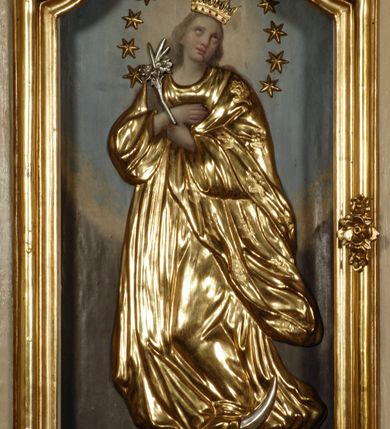 Zdjęcie nr 24: Ołtarz przyścienny, narożny, usytuowany po lewej stronie, w pierwszym od prezbiterium przęśle nawy, przy ścianie tęczowej. Architektoniczny, jednokondygnacyjny ze zwieńczeniem. Mensa murowana, prostopadłościenna, w typie skrzyniowym, z relikwiami nieznanego z imienia świętego męczennika. Antepedium z blachy w drewnianej ramie, z monogramem maryjnym w centrum. Niewielkie, drewniane tabernakulum jednodrzwiowe; lekko wypukłe drzwiczki zdobione płaskorzeźbionym kielichem z hostią wkomponowanym w złoconą płycinę zamkniętą łukiem nadwieszonym. Boki tabernakulum ujęte wolutowymi esownicami ustawionymi ukośnie w stosunku do jego lica. Zwieńczenie w formie przeciwstawnych wolut zdobionych rocaille&#039;em. Nastawa ołtarzowa wsparta na flankujących mensę wysokich, dwudzielnych postumentach dekorowanych złoconymi płycinami zdobionymi rocaille&#039;em. Części boczne na całej wysokości ustawione ukośnie w stosunku do osi środkowej ołtarza. Wysunięte przed zdwojone pilastry z trzonami dekorowanymi rocaille&#039;ami, kolumny o kanelowanych na całej wysokości, złoconych trzonach i kompozytowych kapitelach, dźwigają bogato profilowane, gierowane, pełne belkowanie, wyłamane na osi podpór. Wieńczy je przerwany, półkolisty przyczółek. W polu nastawy złocona, profilowana rama o kształcie stojącego prostokąta zamkniętego łukiem wklęsło-wypukłym z uskokiem. Na jej boku, z prawej strony nałożona złocona aplikacja kwiatowa. Wewnątrz wysuwane dwa obrazy: z Matką Boską Niepokalanie Poczętą i Aniołem Stróżem (obecnie wyjęty) pędzla Wojciecha Eljasza-Radzikowskiego. Na belkowaniu osadzony rocaille&#039;owy kartusz. Zwieńczenie o wykrojonych wolutowo bokach zamknięte łukiem wklęsło-wypukłym utworzonym przez dwie przeciwstawne woluty. U szczytu złocona, ażurowo wycinana, muszla palmetowa. W polu obraz na blasze ze św. Antonim Padewskim i Dzieciątkiem Jezus w kształcie stojącego prostokąta o ściętych krawędziach dolnych i wklęsłych bokach, zamkniętego łukiem wklęsło-wypukłym z uskokiem. Flankują go dwie, niewielkie aplikacje rocaille&#039;owe. Na tylnych postumentach cokołu dwie dużych rozmiarów, pełnoplastyczne rzeźby aniołów. Postaci stojące w silnym kontrapoście, o tanecznych, dynamicznych pozach. Ciała muskularne, odziane w bogate, złocone, mocno fałdowane szaty. Skrzydła złocone, karnacje polichromowane. Po obu bokach ołtarza niewielkie uszy utworzone z rocaille&#039;ów. Ołtarz obecnie przemalowany na kremowo. Ornamenty, załamania profili, ramy, trzony kolumn złocone.