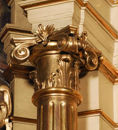 Zdjęcie nr 13: Ołtarz przyścienny, narożny, usytuowany po lewej stronie, w pierwszym od prezbiterium przęśle nawy, przy ścianie tęczowej. Architektoniczny, jednokondygnacyjny ze zwieńczeniem. Mensa murowana, prostopadłościenna, w typie skrzyniowym, z relikwiami nieznanego z imienia świętego męczennika. Antepedium z blachy w drewnianej ramie, z monogramem maryjnym w centrum. Niewielkie, drewniane tabernakulum jednodrzwiowe; lekko wypukłe drzwiczki zdobione płaskorzeźbionym kielichem z hostią wkomponowanym w złoconą płycinę zamkniętą łukiem nadwieszonym. Boki tabernakulum ujęte wolutowymi esownicami ustawionymi ukośnie w stosunku do jego lica. Zwieńczenie w formie przeciwstawnych wolut zdobionych rocaille'em. Nastawa ołtarzowa wsparta na flankujących mensę wysokich, dwudzielnych postumentach dekorowanych złoconymi płycinami zdobionymi rocaille'em. Części boczne na całej wysokości ustawione ukośnie w stosunku do osi środkowej ołtarza. Wysunięte przed zdwojone pilastry z trzonami dekorowanymi rocaille'ami, kolumny o kanelowanych na całej wysokości, złoconych trzonach i kompozytowych kapitelach, dźwigają bogato profilowane, gierowane, pełne belkowanie, wyłamane na osi podpór. Wieńczy je przerwany, półkolisty przyczółek. W polu nastawy złocona, profilowana rama o kształcie stojącego prostokąta zamkniętego łukiem wklęsło-wypukłym z uskokiem. Na jej boku, z prawej strony nałożona złocona aplikacja kwiatowa. Wewnątrz wysuwane dwa obrazy: z Matką Boską Niepokalanie Poczętą i Aniołem Stróżem (obecnie wyjęty) pędzla Wojciecha Eljasza-Radzikowskiego. Na belkowaniu osadzony rocaille'owy kartusz. Zwieńczenie o wykrojonych wolutowo bokach zamknięte łukiem wklęsło-wypukłym utworzonym przez dwie przeciwstawne woluty. U szczytu złocona, ażurowo wycinana, muszla palmetowa. W polu obraz na blasze ze św. Antonim Padewskim i Dzieciątkiem Jezus w kształcie stojącego prostokąta o ściętych krawędziach dolnych i wklęsłych bokach, zamkniętego łukiem wklęsło-wypukłym z uskokiem. Flankują go dwie, niewielkie aplikacje rocaille'owe. Na tylnych postumentach cokołu dwie dużych rozmiarów, pełnoplastyczne rzeźby aniołów. Postaci stojące w silnym kontrapoście, o tanecznych, dynamicznych pozach. Ciała muskularne, odziane w bogate, złocone, mocno fałdowane szaty. Skrzydła złocone, karnacje polichromowane. Po obu bokach ołtarza niewielkie uszy utworzone z rocaille'ów. Ołtarz obecnie przemalowany na kremowo. Ornamenty, załamania profili, ramy, trzony kolumn złocone.