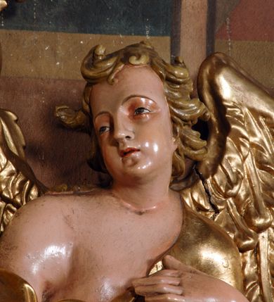 Zdjęcie nr 11: Ołtarz przyścienny, narożny, usytuowany po lewej stronie, w pierwszym od prezbiterium przęśle nawy, przy ścianie tęczowej. Architektoniczny, jednokondygnacyjny ze zwieńczeniem. Mensa murowana, prostopadłościenna, w typie skrzyniowym, z relikwiami nieznanego z imienia świętego męczennika. Antepedium z blachy w drewnianej ramie, z monogramem maryjnym w centrum. Niewielkie, drewniane tabernakulum jednodrzwiowe; lekko wypukłe drzwiczki zdobione płaskorzeźbionym kielichem z hostią wkomponowanym w złoconą płycinę zamkniętą łukiem nadwieszonym. Boki tabernakulum ujęte wolutowymi esownicami ustawionymi ukośnie w stosunku do jego lica. Zwieńczenie w formie przeciwstawnych wolut zdobionych rocaille&#039;em. Nastawa ołtarzowa wsparta na flankujących mensę wysokich, dwudzielnych postumentach dekorowanych złoconymi płycinami zdobionymi rocaille&#039;em. Części boczne na całej wysokości ustawione ukośnie w stosunku do osi środkowej ołtarza. Wysunięte przed zdwojone pilastry z trzonami dekorowanymi rocaille&#039;ami, kolumny o kanelowanych na całej wysokości, złoconych trzonach i kompozytowych kapitelach, dźwigają bogato profilowane, gierowane, pełne belkowanie, wyłamane na osi podpór. Wieńczy je przerwany, półkolisty przyczółek. W polu nastawy złocona, profilowana rama o kształcie stojącego prostokąta zamkniętego łukiem wklęsło-wypukłym z uskokiem. Na jej boku, z prawej strony nałożona złocona aplikacja kwiatowa. Wewnątrz wysuwane dwa obrazy: z Matką Boską Niepokalanie Poczętą i Aniołem Stróżem (obecnie wyjęty) pędzla Wojciecha Eljasza-Radzikowskiego. Na belkowaniu osadzony rocaille&#039;owy kartusz. Zwieńczenie o wykrojonych wolutowo bokach zamknięte łukiem wklęsło-wypukłym utworzonym przez dwie przeciwstawne woluty. U szczytu złocona, ażurowo wycinana, muszla palmetowa. W polu obraz na blasze ze św. Antonim Padewskim i Dzieciątkiem Jezus w kształcie stojącego prostokąta o ściętych krawędziach dolnych i wklęsłych bokach, zamkniętego łukiem wklęsło-wypukłym z uskokiem. Flankują go dwie, niewielkie aplikacje rocaille&#039;owe. Na tylnych postumentach cokołu dwie dużych rozmiarów, pełnoplastyczne rzeźby aniołów. Postaci stojące w silnym kontrapoście, o tanecznych, dynamicznych pozach. Ciała muskularne, odziane w bogate, złocone, mocno fałdowane szaty. Skrzydła złocone, karnacje polichromowane. Po obu bokach ołtarza niewielkie uszy utworzone z rocaille&#039;ów. Ołtarz obecnie przemalowany na kremowo. Ornamenty, załamania profili, ramy, trzony kolumn złocone.