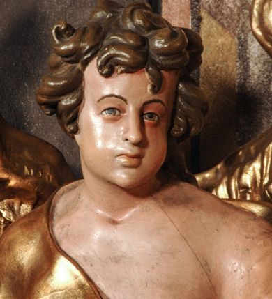 Zdjęcie nr 17: Ołtarz przyścienny, narożny, usytuowany po lewej stronie, w pierwszym od prezbiterium przęśle nawy, przy ścianie tęczowej. Architektoniczny, jednokondygnacyjny ze zwieńczeniem. Mensa murowana, prostopadłościenna, w typie skrzyniowym, z relikwiami nieznanego z imienia świętego męczennika. Antepedium z blachy w drewnianej ramie, z monogramem maryjnym w centrum. Niewielkie, drewniane tabernakulum jednodrzwiowe; lekko wypukłe drzwiczki zdobione płaskorzeźbionym kielichem z hostią wkomponowanym w złoconą płycinę zamkniętą łukiem nadwieszonym. Boki tabernakulum ujęte wolutowymi esownicami ustawionymi ukośnie w stosunku do jego lica. Zwieńczenie w formie przeciwstawnych wolut zdobionych rocaille'em. Nastawa ołtarzowa wsparta na flankujących mensę wysokich, dwudzielnych postumentach dekorowanych złoconymi płycinami zdobionymi rocaille'em. Części boczne na całej wysokości ustawione ukośnie w stosunku do osi środkowej ołtarza. Wysunięte przed zdwojone pilastry z trzonami dekorowanymi rocaille'ami, kolumny o kanelowanych na całej wysokości, złoconych trzonach i kompozytowych kapitelach, dźwigają bogato profilowane, gierowane, pełne belkowanie, wyłamane na osi podpór. Wieńczy je przerwany, półkolisty przyczółek. W polu nastawy złocona, profilowana rama o kształcie stojącego prostokąta zamkniętego łukiem wklęsło-wypukłym z uskokiem. Na jej boku, z prawej strony nałożona złocona aplikacja kwiatowa. Wewnątrz wysuwane dwa obrazy: z Matką Boską Niepokalanie Poczętą i Aniołem Stróżem (obecnie wyjęty) pędzla Wojciecha Eljasza-Radzikowskiego. Na belkowaniu osadzony rocaille'owy kartusz. Zwieńczenie o wykrojonych wolutowo bokach zamknięte łukiem wklęsło-wypukłym utworzonym przez dwie przeciwstawne woluty. U szczytu złocona, ażurowo wycinana, muszla palmetowa. W polu obraz na blasze ze św. Antonim Padewskim i Dzieciątkiem Jezus w kształcie stojącego prostokąta o ściętych krawędziach dolnych i wklęsłych bokach, zamkniętego łukiem wklęsło-wypukłym z uskokiem. Flankują go dwie, niewielkie aplikacje rocaille'owe. Na tylnych postumentach cokołu dwie dużych rozmiarów, pełnoplastyczne rzeźby aniołów. Postaci stojące w silnym kontrapoście, o tanecznych, dynamicznych pozach. Ciała muskularne, odziane w bogate, złocone, mocno fałdowane szaty. Skrzydła złocone, karnacje polichromowane. Po obu bokach ołtarza niewielkie uszy utworzone z rocaille'ów. Ołtarz obecnie przemalowany na kremowo. Ornamenty, załamania profili, ramy, trzony kolumn złocone.