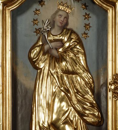 Zdjęcie nr 1: Obraz umieszczony w polu lewego ołtarza bocznego w pierwszym od prezbiterium przęśle nawy kościoła, w kształcie stojącego prostokąta zamkniętego łukiem wklęsło-wypukłym z uskokiem, w profilowanej, złoconej ramie. W centrum stojąca, ukazana frontalnie, całopostaciowo Maria w typie Niepokalanie Poczętej. Postać stojąca na półksiężycu, z głową lekko odchyloną ku górze, skierowaną w prawą stronę i rękoma skrzyżowanymi na piersi. W lewej dłoni trzyma rzeźbioną, srebrzoną lilię. Twarz drobna, okrągła z wypukłym czołem, dużymi, okrągłymi oczami wzniesionymi ku górze i niewielkimi, pełnymi ustami. Policzki zaakcentowane różem. Włosy długie, opadające na plecy w kolorze szaro-brązowym. Maria jest ubrana w obszerne, długie, rozwiane szaty nakładane na obraz drewniane, złocone. Składają się na nie płaszcz i długa suknia. Na głowie drewniana, złocona korona otwarta z rzeźbionymi szlachetnymi kamieniami. Wokół głowy okrąg z 12 drewnianych i złoconych gwiazd. W dole kompozycji płaskorzeźbiony, srebrzony półksiężyc, oraz złocone glob i wąż z jabłkiem w paszczy. Tło malowane, nieokreślonej barwy brązowo-niebieskiej, rozjaśnione wokół głowy Marii i u dołu kompozycji.