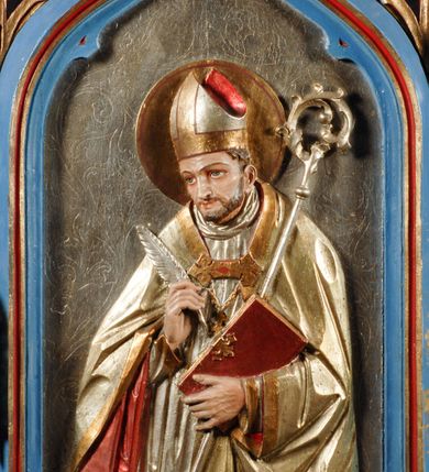 Zdjęcie nr 4: Feretron ma formy architektonczne. Podstawę flankuje para niewysokich, wielobocznych cokołów, nakrywa zaś gzyms wieńczący. Obrazy feretronu ujęte są profilowaną, polichromowaną i złoconą ramą w kształcie prostokąta zamkniętego łukiem w ośli grzbiet, zwieńczonym kwiatonem z krzyżem. Dodatkowo flankowana parą pełnoplastycznych, zwróconych w lustrzanym odbiciu na zewnątrz figurek aniołów stojących na niewysokich postumentach pod ozdobnymi baldachimami zwieńczonymi ażurowymi pinaklami z kwiatonami. Dodatkowo krawędzie łuku ramy zdobi ażurowy motyw astwerkowy. Detale architektoniczne pokrywa niebieska i czerwona polichromia oraz złocenia. Na awersie znajduje się płaskorzeźba Matki Boskiej Nieustającej Pomocy. Maria ukazana jest w półpostaci, frontalnie, z Dzieciątkiem na lewej ręce. Lekko przechyloną w prawo głową charakteryzuje twarz o młodzieńczych rysach i wyrazistych, ciemnych oczach. Maria ubrana jest w czerwoną suknię, błękitny, zarzucony na głowę płaszcz układający się rytmicznymi fałdami, dodatkowo głowę wieńczy korona, a wokół nie jest nimb. Prawą dłonią ujmuje dłonie tulącego się do niej i spoglądającego w prawo Dzieciątka. Jezus ubrany jest w złotą szatę, na stopie ma jeden, zsuwający się sandał. Charakteryzują go dziecięce rysy oraz krótkie, brązowe włosy. Na głowie ma koronę. Po obydwu stronach postaci widoczne są  niewielkie sylwetki aniołów w długich szatach trzymające w dłoniach krzyż oraz włócznię z gąbką i naczynie. Tło jest złocone.
 Na rewersie jest płaskorzeźbiony wizerunek św. biskupa ukazanego w półpostaci, frontalnie. Przechyloną w lewo głowę charakteryzuje wyraziście opracowana twarz z krótkim zarostem. Święty ubrany jest w srebrną suknię z krzyżem na piersi i jasnożółtą kapę z czerwoną podszewką, spiętą powyżej pektorału. Na głowie ma mitrę biskupią, wokół głowy nimb. W prawej dłoni trzyma pióro, zaś lewą podtrzymuje czerwoną księgę ze złoconymi okuciami i srebrny pastorał. Tło jest srebrne, z grawerowanym ornamentem akantowym. Płaskorzeźby i boczne anioły pokryte laserunkową malaturą.