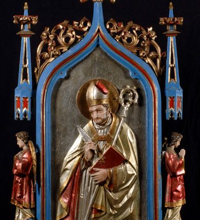 Zdjęcie nr 3: Feretron ma formy architektonczne. Podstawę flankuje para niewysokich, wielobocznych cokołów, nakrywa zaś gzyms wieńczący. Obrazy feretronu ujęte są profilowaną, polichromowaną i złoconą ramą w kształcie prostokąta zamkniętego łukiem w ośli grzbiet, zwieńczonym kwiatonem z krzyżem. Dodatkowo flankowana parą pełnoplastycznych, zwróconych w lustrzanym odbiciu na zewnątrz figurek aniołów stojących na niewysokich postumentach pod ozdobnymi baldachimami zwieńczonymi ażurowymi pinaklami z kwiatonami. Dodatkowo krawędzie łuku ramy zdobi ażurowy motyw astwerkowy. Detale architektoniczne pokrywa niebieska i czerwona polichromia oraz złocenia. Na awersie znajduje się płaskorzeźba Matki Boskiej Nieustającej Pomocy. Maria ukazana jest w półpostaci, frontalnie, z Dzieciątkiem na lewej ręce. Lekko przechyloną w prawo głową charakteryzuje twarz o młodzieńczych rysach i wyrazistych, ciemnych oczach. Maria ubrana jest w czerwoną suknię, błękitny, zarzucony na głowę płaszcz układający się rytmicznymi fałdami, dodatkowo głowę wieńczy korona, a wokół nie jest nimb. Prawą dłonią ujmuje dłonie tulącego się do niej i spoglądającego w prawo Dzieciątka. Jezus ubrany jest w złotą szatę, na stopie ma jeden, zsuwający się sandał. Charakteryzują go dziecięce rysy oraz krótkie, brązowe włosy. Na głowie ma koronę. Po obydwu stronach postaci widoczne są  niewielkie sylwetki aniołów w długich szatach trzymające w dłoniach krzyż oraz włócznię z gąbką i naczynie. Tło jest złocone.
 Na rewersie jest płaskorzeźbiony wizerunek św. biskupa ukazanego w półpostaci, frontalnie. Przechyloną w lewo głowę charakteryzuje wyraziście opracowana twarz z krótkim zarostem. Święty ubrany jest w srebrną suknię z krzyżem na piersi i jasnożółtą kapę z czerwoną podszewką, spiętą powyżej pektorału. Na głowie ma mitrę biskupią, wokół głowy nimb. W prawej dłoni trzyma pióro, zaś lewą podtrzymuje czerwoną księgę ze złoconymi okuciami i srebrny pastorał. Tło jest srebrne, z grawerowanym ornamentem akantowym. Płaskorzeźby i boczne anioły pokryte laserunkową malaturą.