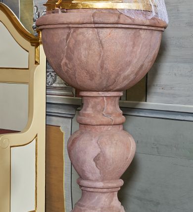 Zdjęcie nr 1: Stopa wysoka, na planie ośmioboku, w górnej części profilowana. Trzon w kształcie balaski, nodus owoidalny, ujęty dwoma pierścieniami. Czara półkolista, gładka z wywiniętą wargą. Wewnątrz miedziana misa. Pokrywa współczesna w formie ośmiobocznej kopuły, zdobionej motywem rybiej łuski, zwieńczona kulą z krzyżem. Kamienna chrzcielnica marmoryzowana; pokrywa złocona.