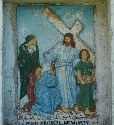 Zdjęcie nr 8: Stacje drogi krzyżowej zamontowane w prostokątnych wnękach muru przykościelnego. Kompozycje kilkupostaciowe ukazane na jednolitym, błękitnym tle. Nad każdą stacją krzyżową umieszczone proste, drewniane krzyżyki. U dołu stacji rzeźbione, malowane na czarno inskrypcje:
1. „+JEZUS NA ŚMIERĆ OSĄDZONY+”;
2. „JEZUS KRZYŻEM OBCIĄŻONY+”;
3. „+JEZUS PIERWSZY RAZ UPADA+”;
4. „+JEZUS SPOTYKA MATKĘ SWĄ+”;
5. „CYRENEJCZYK POMAGA JEZUSOWI”;
6. „WERONIKA OCIERA TWARZ JEZUSA”;
7. „JEZUS DRUGI RAZ UPADA”(inskrypcja prawie nieczytelna);
8. „JEZUS POCIESZA NIEWIASTY”;
9. „++JEZUS TRZECI RAZ UPADA++”;
10. „++JEZUS Z SZAT OBNAŻONY++”;
11. „+JEZUS DO KRZYŻA PRZYBITY+”;
12. „INRI / ++JEZUS NA KRZYŻU UMIERA” (inskrypcja prawie nieczytelna);
13. „INRI / ++JEZUS Z KRZYŻA ZDJĘTY++”;
14. (Brak fotografii).

