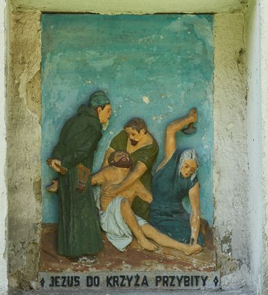 Zdjęcie nr 11: Stacje drogi krzyżowej zamontowane w prostokątnych wnękach muru przykościelnego. Kompozycje kilkupostaciowe ukazane na jednolitym, błękitnym tle. Nad każdą stacją krzyżową umieszczone proste, drewniane krzyżyki. U dołu stacji rzeźbione, malowane na czarno inskrypcje:
1. „+JEZUS NA ŚMIERĆ OSĄDZONY+”;
2. „JEZUS KRZYŻEM OBCIĄŻONY+”;
3. „+JEZUS PIERWSZY RAZ UPADA+”;
4. „+JEZUS SPOTYKA MATKĘ SWĄ+”;
5. „CYRENEJCZYK POMAGA JEZUSOWI”;
6. „WERONIKA OCIERA TWARZ JEZUSA”;
7. „JEZUS DRUGI RAZ UPADA”(inskrypcja prawie nieczytelna);
8. „JEZUS POCIESZA NIEWIASTY”;
9. „++JEZUS TRZECI RAZ UPADA++”;
10. „++JEZUS Z SZAT OBNAŻONY++”;
11. „+JEZUS DO KRZYŻA PRZYBITY+”;
12. „INRI / ++JEZUS NA KRZYŻU UMIERA” (inskrypcja prawie nieczytelna);
13. „INRI / ++JEZUS Z KRZYŻA ZDJĘTY++”;
14. (Brak fotografii).

