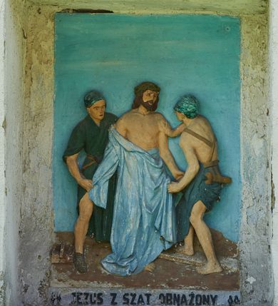 Zdjęcie nr 10: Stacje drogi krzyżowej zamontowane w prostokątnych wnękach muru przykościelnego. Kompozycje kilkupostaciowe ukazane na jednolitym, błękitnym tle. Nad każdą stacją krzyżową umieszczone proste, drewniane krzyżyki. U dołu stacji rzeźbione, malowane na czarno inskrypcje:
1. „+JEZUS NA ŚMIERĆ OSĄDZONY+”;
2. „JEZUS KRZYŻEM OBCIĄŻONY+”;
3. „+JEZUS PIERWSZY RAZ UPADA+”;
4. „+JEZUS SPOTYKA MATKĘ SWĄ+”;
5. „CYRENEJCZYK POMAGA JEZUSOWI”;
6. „WERONIKA OCIERA TWARZ JEZUSA”;
7. „JEZUS DRUGI RAZ UPADA”(inskrypcja prawie nieczytelna);
8. „JEZUS POCIESZA NIEWIASTY”;
9. „++JEZUS TRZECI RAZ UPADA++”;
10. „++JEZUS Z SZAT OBNAŻONY++”;
11. „+JEZUS DO KRZYŻA PRZYBITY+”;
12. „INRI / ++JEZUS NA KRZYŻU UMIERA” (inskrypcja prawie nieczytelna);
13. „INRI / ++JEZUS Z KRZYŻA ZDJĘTY++”;
14. (Brak fotografii).

