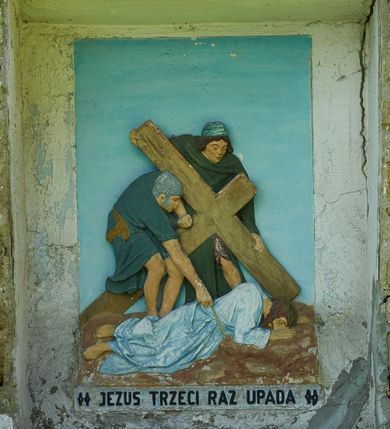 Zdjęcie nr 12: Stacje drogi krzyżowej zamontowane w prostokątnych wnękach muru przykościelnego. Kompozycje kilkupostaciowe ukazane na jednolitym, błękitnym tle. Nad każdą stacją krzyżową umieszczone proste, drewniane krzyżyki. U dołu stacji rzeźbione, malowane na czarno inskrypcje:
1. „+JEZUS NA ŚMIERĆ OSĄDZONY+”;
2. „JEZUS KRZYŻEM OBCIĄŻONY+”;
3. „+JEZUS PIERWSZY RAZ UPADA+”;
4. „+JEZUS SPOTYKA MATKĘ SWĄ+”;
5. „CYRENEJCZYK POMAGA JEZUSOWI”;
6. „WERONIKA OCIERA TWARZ JEZUSA”;
7. „JEZUS DRUGI RAZ UPADA”(inskrypcja prawie nieczytelna);
8. „JEZUS POCIESZA NIEWIASTY”;
9. „++JEZUS TRZECI RAZ UPADA++”;
10. „++JEZUS Z SZAT OBNAŻONY++”;
11. „+JEZUS DO KRZYŻA PRZYBITY+”;
12. „INRI / ++JEZUS NA KRZYŻU UMIERA” (inskrypcja prawie nieczytelna);
13. „INRI / ++JEZUS Z KRZYŻA ZDJĘTY++”;
14. (Brak fotografii).

