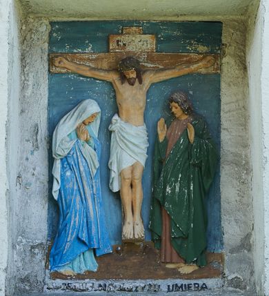 Zdjęcie nr 13: Stacje drogi krzyżowej zamontowane w prostokątnych wnękach muru przykościelnego. Kompozycje kilkupostaciowe ukazane na jednolitym, błękitnym tle. Nad każdą stacją krzyżową umieszczone proste, drewniane krzyżyki. U dołu stacji rzeźbione, malowane na czarno inskrypcje:
1. „+JEZUS NA ŚMIERĆ OSĄDZONY+”;
2. „JEZUS KRZYŻEM OBCIĄŻONY+”;
3. „+JEZUS PIERWSZY RAZ UPADA+”;
4. „+JEZUS SPOTYKA MATKĘ SWĄ+”;
5. „CYRENEJCZYK POMAGA JEZUSOWI”;
6. „WERONIKA OCIERA TWARZ JEZUSA”;
7. „JEZUS DRUGI RAZ UPADA”(inskrypcja prawie nieczytelna);
8. „JEZUS POCIESZA NIEWIASTY”;
9. „++JEZUS TRZECI RAZ UPADA++”;
10. „++JEZUS Z SZAT OBNAŻONY++”;
11. „+JEZUS DO KRZYŻA PRZYBITY+”;
12. „INRI / ++JEZUS NA KRZYŻU UMIERA” (inskrypcja prawie nieczytelna);
13. „INRI / ++JEZUS Z KRZYŻA ZDJĘTY++”;
14. (Brak fotografii).

