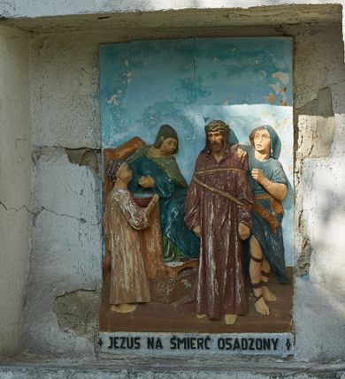 Zdjęcie nr 3: Stacje drogi krzyżowej zamontowane w prostokątnych wnękach muru przykościelnego. Kompozycje kilkupostaciowe ukazane na jednolitym, błękitnym tle. Nad każdą stacją krzyżową umieszczone proste, drewniane krzyżyki. U dołu stacji rzeźbione, malowane na czarno inskrypcje:
1. „+JEZUS NA ŚMIERĆ OSĄDZONY+”;
2. „JEZUS KRZYŻEM OBCIĄŻONY+”;
3. „+JEZUS PIERWSZY RAZ UPADA+”;
4. „+JEZUS SPOTYKA MATKĘ SWĄ+”;
5. „CYRENEJCZYK POMAGA JEZUSOWI”;
6. „WERONIKA OCIERA TWARZ JEZUSA”;
7. „JEZUS DRUGI RAZ UPADA”(inskrypcja prawie nieczytelna);
8. „JEZUS POCIESZA NIEWIASTY”;
9. „++JEZUS TRZECI RAZ UPADA++”;
10. „++JEZUS Z SZAT OBNAŻONY++”;
11. „+JEZUS DO KRZYŻA PRZYBITY+”;
12. „INRI / ++JEZUS NA KRZYŻU UMIERA” (inskrypcja prawie nieczytelna);
13. „INRI / ++JEZUS Z KRZYŻA ZDJĘTY++”;
14. (Brak fotografii).

