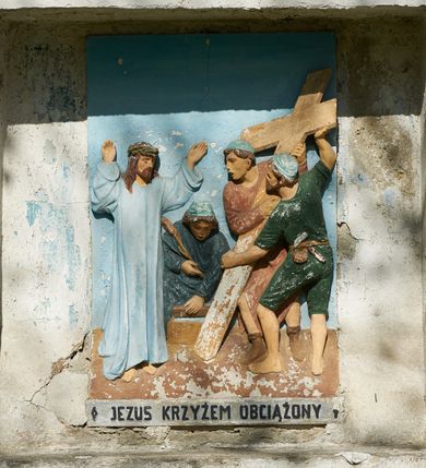 Zdjęcie nr 5: Stacje drogi krzyżowej zamontowane w prostokątnych wnękach muru przykościelnego. Kompozycje kilkupostaciowe ukazane na jednolitym, błękitnym tle. Nad każdą stacją krzyżową umieszczone proste, drewniane krzyżyki. U dołu stacji rzeźbione, malowane na czarno inskrypcje:
1. „+JEZUS NA ŚMIERĆ OSĄDZONY+”;
2. „JEZUS KRZYŻEM OBCIĄŻONY+”;
3. „+JEZUS PIERWSZY RAZ UPADA+”;
4. „+JEZUS SPOTYKA MATKĘ SWĄ+”;
5. „CYRENEJCZYK POMAGA JEZUSOWI”;
6. „WERONIKA OCIERA TWARZ JEZUSA”;
7. „JEZUS DRUGI RAZ UPADA”(inskrypcja prawie nieczytelna);
8. „JEZUS POCIESZA NIEWIASTY”;
9. „++JEZUS TRZECI RAZ UPADA++”;
10. „++JEZUS Z SZAT OBNAŻONY++”;
11. „+JEZUS DO KRZYŻA PRZYBITY+”;
12. „INRI / ++JEZUS NA KRZYŻU UMIERA” (inskrypcja prawie nieczytelna);
13. „INRI / ++JEZUS Z KRZYŻA ZDJĘTY++”;
14. (Brak fotografii).

