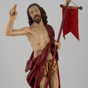 Zdjęcie nr 1: Rzeźba pełna, ustawiona na niskim, kwadratowym, profilowanym cokole. Chrystus ukazany frontalnie, stojący na kawałku zielonej murawy, w kontrapoście, z głową zwróconą w prawo. W lewej, ugiętej ręce trzyma chorągiew; prawa, uniesiona jest wysoko w geście błogosławieństwa. Twarz pociągła, okolona brodą, z na wpół przymkniętymi oczami; włosy długie, kręcone opadają na ramiona. Ciało wychudzone, z zaznaczonymi śladami męki i podkreśloną linią żeber. Przez lewe ramię przerzucony czerwony płaszcz spływający na plecy i z przodu na lewe przedramię; na biodrach złocone  perizonium, ciasno oplecione. Polichromia ciała jest naturalistyczna, perizonium złocone.
