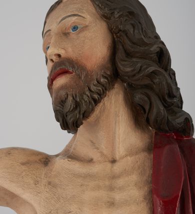 Zdjęcie nr 5: Rzeźba pełna, ustawiona na niskim, kwadratowym, profilowanym cokole. Chrystus ukazany frontalnie, stojący na kawałku zielonej murawy, w kontrapoście, z głową zwróconą w prawo. W lewej, ugiętej ręce trzyma chorągiew; prawa, uniesiona jest wysoko w geście błogosławieństwa. Twarz pociągła, okolona brodą, z na wpół przymkniętymi oczami; włosy długie, kręcone opadają na ramiona. Ciało wychudzone, z zaznaczonymi śladami męki i podkreśloną linią żeber. Przez lewe ramię przerzucony czerwony płaszcz spływający na plecy i z przodu na lewe przedramię; na biodrach złocone  perizonium, ciasno oplecione. Polichromia ciała jest naturalistyczna, perizonium złocone.