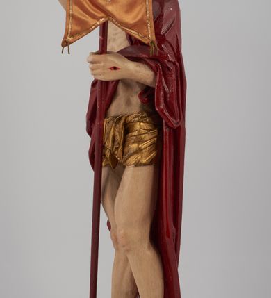 Zdjęcie nr 12: Rzeźba pełna, ustawiona na niskim, kwadratowym, profilowanym cokole. Chrystus ukazany frontalnie, stojący na kawałku zielonej murawy, w kontrapoście, z głową zwróconą w prawo. W lewej, ugiętej ręce trzyma chorągiew; prawa, uniesiona jest wysoko w geście błogosławieństwa. Twarz pociągła, okolona brodą, z na wpół przymkniętymi oczami; włosy długie, kręcone opadają na ramiona. Ciało wychudzone, z zaznaczonymi śladami męki i podkreśloną linią żeber. Przez lewe ramię przerzucony czerwony płaszcz spływający na plecy i z przodu na lewe przedramię; na biodrach złocone  perizonium, ciasno oplecione. Polichromia ciała jest naturalistyczna, perizonium złocone.