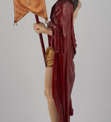 Zdjęcie nr 13: Rzeźba pełna, ustawiona na niskim, kwadratowym, profilowanym cokole. Chrystus ukazany frontalnie, stojący na kawałku zielonej murawy, w kontrapoście, z głową zwróconą w prawo. W lewej, ugiętej ręce trzyma chorągiew; prawa, uniesiona jest wysoko w geście błogosławieństwa. Twarz pociągła, okolona brodą, z na wpół przymkniętymi oczami; włosy długie, kręcone opadają na ramiona. Ciało wychudzone, z zaznaczonymi śladami męki i podkreśloną linią żeber. Przez lewe ramię przerzucony czerwony płaszcz spływający na plecy i z przodu na lewe przedramię; na biodrach złocone  perizonium, ciasno oplecione. Polichromia ciała jest naturalistyczna, perizonium złocone.