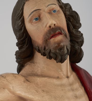 Zdjęcie nr 4: Rzeźba pełna, ustawiona na niskim, kwadratowym, profilowanym cokole. Chrystus ukazany frontalnie, stojący na kawałku zielonej murawy, w kontrapoście, z głową zwróconą w prawo. W lewej, ugiętej ręce trzyma chorągiew; prawa, uniesiona jest wysoko w geście błogosławieństwa. Twarz pociągła, okolona brodą, z na wpół przymkniętymi oczami; włosy długie, kręcone opadają na ramiona. Ciało wychudzone, z zaznaczonymi śladami męki i podkreśloną linią żeber. Przez lewe ramię przerzucony czerwony płaszcz spływający na plecy i z przodu na lewe przedramię; na biodrach złocone  perizonium, ciasno oplecione. Polichromia ciała jest naturalistyczna, perizonium złocone.