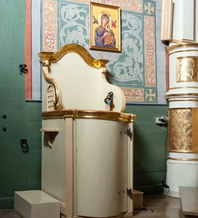 Zdjęcie nr 2: Konfesjonał usytuowany w nawie głównej, przy ścianie północnej. Podstawa na planie zbliżonym do kwadratu, z przodu zakończona linią wklęsło-wypukłą. Drzwi zamykające wejście do siedziska wypukłe, zakończone profilowanym gzymsem, ujęte po bokach ukośnie ustawionymi lizenami. Boczne, występujące ku górze ścianki ograniczające siedzisko zwieńczone fantazyjnymi łukami wklęsło-wypukłymi zakończonymi ślimacznicami. Ściana zaplecka zakończona profilowanym gzymsem w kształcie łuku wklęsło-wypukłego. Po bokach konfesjonału dostawione, wolnostojące klęczniki w formie prostopadłościanów. W ściankach flankujących z boków siedzisko księdza prześwity z grubą kratą, w kształcie stojącego prostokąta, zamkniętego łukiem ostrym, ujęte prostą ramą. Konfesjonał polichromowany w kolorze beżowym, profilowania złocone. 

