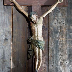 Zdjęcie nr 1: Rzeźba pełna, Chrystus ukazany jako umarły, przybity do krzyża trzema gwoździami. Ciało zawieszone na rozpiętych ramionach o układzie zbliżonym do litery „Y”. Głowa Chrystusa opada na prawe ramię, nogi są delikatnie ugięte w kolanach. Twarz podłużna z zamkniętymi oczami, długim nosem i otwartymi ustami; okolona krótką i brązową brodą. Włosy zawinięte do tyłu i opadające na prawe ramię. Na głowie założona zielona korona cierniowa. Korpus o silnie podkreślonej muskulaturze. W prawym boku głęboka, pionowa rana z zaznaczonymi poniżej wypukłymi kroplami krwi. Perizonium z wywiniętą górną częścią, przewiązane na prawym biodrze i z jednym końcem opadającym wzdłuż prawego uda. Stopy przebite jednym gwoździem, w układzie prawa na lewą. Titulus w formie ukośnie zawieszonej wstęgi o rozdwojonych zakończeniach, w polu napis „INRI”. Polichromia ciała naturalistyczna, perizonium i korona zielone. Krzyż gładki, malowany na brązowo. 
