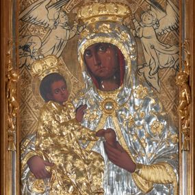 Zdjęcie nr 1: Obraz w kształcie stojącego prostokąta przedstawiający Matkę Boską z Dzieciątkiem. Maria została ukazana w półpostaci z Dzieciątkiem Jezus na prawym ręku, z gruszką w lewej dłoni, z głową delikatnie przechyloną na prawe ramię i wzrokiem skierowanym na widza. Dzieciątko ukazane jest w pozycji siedzącej, zwrócone trzy czwarte w lewo, lewą rączką sięga po gruszkę trzymaną przez Marię w dłoniach, prawą czyni gest błogosławieństwa. Na postacie Marii i Dzieciątka nałożone są metalowe, złocone i srebrzone sukienki, dekorowane w motywy floralne, a także korony w typie zamkniętym. Karnacje bardzo ciemne. Całość ukazana jest na złotym tle, w którym wyróżniają się koliste, złocone nimby wokół głów Marii i Dzieciątka oraz motywy roślinno-geometryczne zamknięte w rombach ukośnej kratownicy. Symetrycznie po bokach głowy Marii zostali przedstawieni konturowaniem dwaj aniołowie koronujący. Obraz umieszczony jest w profilowanej, złoconej i srebrzonej ramie, zdobionej rzeźbiarską, floralną dekoracją oraz parą aniołków na bokach ramy, ukazanych w postawie stojącej, zwróconych ku środkowi obrazu. 