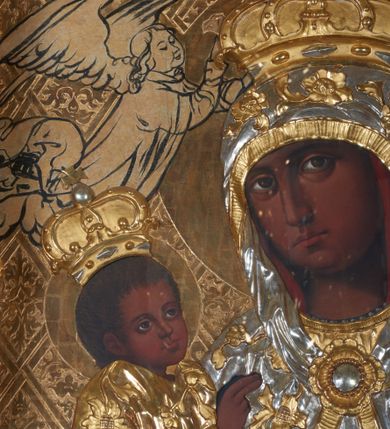 Zdjęcie nr 3: Obraz w kształcie stojącego prostokąta przedstawiający Matkę Boską z Dzieciątkiem. Maria została ukazana w półpostaci z Dzieciątkiem Jezus na prawym ręku, z gruszką w lewej dłoni, z głową delikatnie przechyloną na prawe ramię i wzrokiem skierowanym na widza. Dzieciątko ukazane jest w pozycji siedzącej, zwrócone trzy czwarte w lewo, lewą rączką sięga po gruszkę trzymaną przez Marię w dłoniach, prawą czyni gest błogosławieństwa. Na postacie Marii i Dzieciątka nałożone są metalowe, złocone i srebrzone sukienki, dekorowane w motywy floralne, a także korony w typie zamkniętym. Karnacje bardzo ciemne. Całość ukazana jest na złotym tle, w którym wyróżniają się koliste, złocone nimby wokół głów Marii i Dzieciątka oraz motywy roślinno-geometryczne zamknięte w rombach ukośnej kratownicy. Symetrycznie po bokach głowy Marii zostali przedstawieni konturowaniem dwaj aniołowie koronujący. Obraz umieszczony jest w profilowanej, złoconej i srebrzonej ramie, zdobionej rzeźbiarską, floralną dekoracją oraz parą aniołków na bokach ramy, ukazanych w postawie stojącej, zwróconych ku środkowi obrazu. 