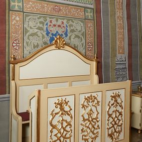 Zdjęcie nr 1: Ława ustawiona na niskim prostopadłościennym podeście, jednorzędowa, trójosobowa, z zapleckiem i z przedpiersiem, zwieńczona dwiema wolutami spinającymi pośrodku palmetę oraz małymi wazonikami ustawionymi na skrajach zaplecka. Przedpiersie przedzielone na trzy płyciny w kształcie stojących prostokątów zdobione w polu stylizowaną wicią z motywami ornamentu pseudoregencyjnego. Zaplecek przedzielony na dwie strefy; w dolnej zdobiony trzema kwadratowymi płycinami, w górnej płyciną w kształcie leżącego prostokąta zamkniętego od góry łukiem wklęsło-wypukłym. 
