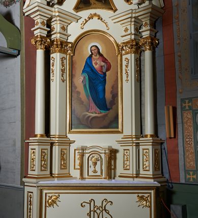Zdjęcie nr 1: Nastawa ołtarzowa architektoniczna, jednoosiowa, jednokondygnacyjna ze zwieńczeniem. Ołtarz prostopadłościenny z kamienną mensą z portatylem. Antepedium drewniane obwiedzione profilowaną ramą z narożami wypełnionymi stylizowanymi liśćmi i wypukło rzeźbionym monogramem IHS pośrodku. Tabernakulum w formie prostopadłościennej skrzynki, flankowane na przodzie parą kolumienek, zamknięte od góry profilowanym gzymsem. Drzwiczki w kształcie stojącego prostokąta z płaskorzeźbionym kielichem z hostią w glorii. Nastawa wsparta na podwójnym, ukośnie ustawionym cokole, podtrzymującym parę zdwojonych filarów i stojących przed nimi parę kolumn. Podpory wspierają imposty i przerywany, wolutowy przyczółek, z usadzoną nań parą aniołków. W polu głównym, w prostokątnej ramie, zamkniętej łukiem nadwieszonym znajduje się obraz „Najświętsze Serce Pana Jezusa” z końca XIX wieku oraz obraz „Trójca Święta” z 1784 roku na zasuwie. Zwieńczenie w kształcie wklęsło-wypukłym, zamkniętym gzymsem utworzonym z dwóch wolut spiętych pośrodku muszlą palmetową. W polu środkowym obraz „Stygmatyzacja św. Franciszka”. W partii cokołu prostokątne płyciny zamknięte profilowanymi ramami z dekoracją floralną w polu, a górne części filarów zdobione ornamentem akantowym. Podpory ustawione na bazach, trzony gładkie, kapitele kompozytowe. Imposty zdobione stylizowanymi rozetami. Struktura polichromowana na kolor jasnobeżowy, detale i ornamentyka złocone.

