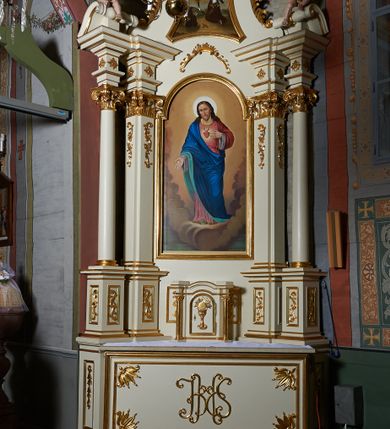Zdjęcie nr 2: Nastawa ołtarzowa architektoniczna, jednoosiowa, jednokondygnacyjna ze zwieńczeniem. Ołtarz prostopadłościenny z kamienną mensą z portatylem. Antepedium drewniane obwiedzione profilowaną ramą z narożami wypełnionymi stylizowanymi liśćmi i wypukło rzeźbionym monogramem IHS pośrodku. Tabernakulum w formie prostopadłościennej skrzynki, flankowane na przodzie parą kolumienek, zamknięte od góry profilowanym gzymsem. Drzwiczki w kształcie stojącego prostokąta z płaskorzeźbionym kielichem z hostią w glorii. Nastawa wsparta na podwójnym, ukośnie ustawionym cokole, podtrzymującym parę zdwojonych filarów i stojących przed nimi parę kolumn. Podpory wspierają imposty i przerywany, wolutowy przyczółek, z usadzoną nań parą aniołków. W polu głównym, w prostokątnej ramie, zamkniętej łukiem nadwieszonym znajduje się obraz „Najświętsze Serce Pana Jezusa” z końca XIX wieku oraz obraz „Trójca Święta” z 1784 roku na zasuwie. Zwieńczenie w kształcie wklęsło-wypukłym, zamkniętym gzymsem utworzonym z dwóch wolut spiętych pośrodku muszlą palmetową. W polu środkowym obraz „Stygmatyzacja św. Franciszka”. W partii cokołu prostokątne płyciny zamknięte profilowanymi ramami z dekoracją floralną w polu, a górne części filarów zdobione ornamentem akantowym. Podpory ustawione na bazach, trzony gładkie, kapitele kompozytowe. Imposty zdobione stylizowanymi rozetami. Struktura polichromowana na kolor jasnobeżowy, detale i ornamentyka złocone.

