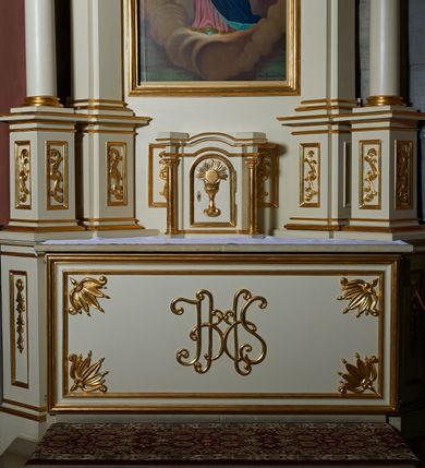Zdjęcie nr 6: Nastawa ołtarzowa architektoniczna, jednoosiowa, jednokondygnacyjna ze zwieńczeniem. Ołtarz prostopadłościenny z kamienną mensą z portatylem. Antepedium drewniane obwiedzione profilowaną ramą z narożami wypełnionymi stylizowanymi liśćmi i wypukło rzeźbionym monogramem IHS pośrodku. Tabernakulum w formie prostopadłościennej skrzynki, flankowane na przodzie parą kolumienek, zamknięte od góry profilowanym gzymsem. Drzwiczki w kształcie stojącego prostokąta z płaskorzeźbionym kielichem z hostią w glorii. Nastawa wsparta na podwójnym, ukośnie ustawionym cokole, podtrzymującym parę zdwojonych filarów i stojących przed nimi parę kolumn. Podpory wspierają imposty i przerywany, wolutowy przyczółek, z usadzoną nań parą aniołków. W polu głównym, w prostokątnej ramie, zamkniętej łukiem nadwieszonym znajduje się obraz „Najświętsze Serce Pana Jezusa” z końca XIX wieku oraz obraz „Trójca Święta” z 1784 roku na zasuwie. Zwieńczenie w kształcie wklęsło-wypukłym, zamkniętym gzymsem utworzonym z dwóch wolut spiętych pośrodku muszlą palmetową. W polu środkowym obraz „Stygmatyzacja św. Franciszka”. W partii cokołu prostokątne płyciny zamknięte profilowanymi ramami z dekoracją floralną w polu, a górne części filarów zdobione ornamentem akantowym. Podpory ustawione na bazach, trzony gładkie, kapitele kompozytowe. Imposty zdobione stylizowanymi rozetami. Struktura polichromowana na kolor jasnobeżowy, detale i ornamentyka złocone.

