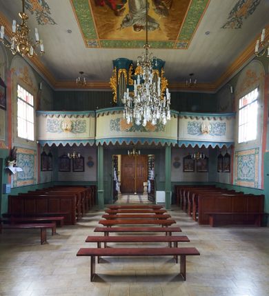 Zdjęcie nr 1: Organy architektoniczne, jednokondygnacyjne, pięcioosiowe. Oś środkowa i skrajne są wypukłe, wydzielone wielobocznymi ryzalitami z prześwitami wypełnionymi piszczałkami; zwieńczone profilowanym gzymsem z uskokami. Analogicznie ukształtowany gzyms ujmuje strukturę od dołu. Ryzality zewnętrzne sięgają stropu, środkowy niższy połączony jest z nimi płaskimi ściankami z prześwitami na piszczałki. Na ścianach bocznych organów płyciny mają ażurową kratkę. Organy ujęte są ażurowymi uszami utworzonymi z rocaille'ów. Oś środkowa ze zwieńczeniem w postaci muszli. Przestrzeń między ryzalitami oraz prześwity w górnej partii wypełniają stylizowane liście akantu. Struktura polichromowana w kolorze ciemnego turkusu; ornamentyka złocona.