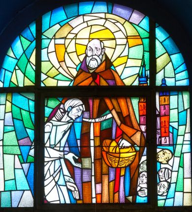 Zdjęcie nr 1: Witraż w kształcie stojącego prostokąta zamkniętego łukiem półkolistym. Kompozycja dwustrefowa, w dolnej nieco z prawej ukazana św. Jadwiga Andegaweńska zwrócona trzy czwarte w prawo z głową odwróconą w drugą stronę z berłem w prawej dłoni. Twarz trójkątna o dużych oczach i długim nosie, okolona długimi jasnobrązowymi włosami. Ubrana jest w długą suknię w odcieniach fioletu oraz purpurowy płaszcz obszyty gronostajem, na głowie ma złotą koronę. Po lewej stronie witrażu widnieje miniatura kamienic krakowskich (być może Collegium Maius Uniwersytetu Jagiellońskiego), poniżej herby Uniwersytetu Jagiellońskiego z syglami „UJ”, Wielkiego Księstwa Litweskiego oraz Królestwa Polskiego. W prawym dolnym narożu inskrypcja „Fundacja / Janina / Józef / Mosórowie”. W górnej partii św. Brat Albert ukazany frontalnie, prawą ręką obejmujący stojącego przed nim ubogiego człowieka, a w lewej trzyma kosz z chlebem. Święty ubrany jest w habit i płaszcz albertynów, przewiązany sznurem. Twarz szeroka, okolona siwą brodą i łysiną. Wokół głowy świętego duży, złocony nimb. Po lewej stronie leży paleta z pędzlem. Po prawej miniatura kościoła Mariackiego i głowy ubogich ludzi. Kolorystyka utrzymana w chłodnych barwach.

