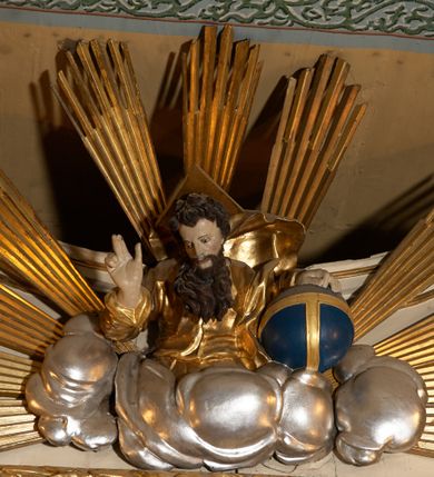 Zdjęcie nr 20: Ołtarz typu architektonicznego, jednokondygnacyjny, jednoosiowy, z bramkami i ze zwieńczeniem w formie glorii. Mensa prostopadłościenna, na ściance przedniej zdobiona rzędem płycin w kształcie stojącego prostokąta, zamkniętych łukiem nadwieszonym. W polu środkowej płyciny malowany krzyż grecki, w pozostałych gałązki białych lilii. Tabernakulum w formie prostopadłościennej skrzynki, z częścią środkową wysuniętą do przodu, zamknięte od góry profilowanym gzymsem w kształcie łuku nadwieszonego. Drzwiczki metalowe, pośrodku dekorowane płyciną w kształcie stojącego prostokąta, zamkniętego łukiem nadwieszonym, w polu kielich z hostią, kłosy zboża i kiście winogron. Nad tabernakulum tron wystawienia na tle promienistej glorii z monogramem IHS pośrodku, po bokach flankowany przez parę aniołków usadzonych na wolutach. Retabulum ustawione na wysokim cokole, ujęte parą zdwojonych, ukośnie ustawionych pilastrów podtrzymujących przerywane belkowanie, na którym usadzona para putt. Trzony pilastrów zdobione kanelowaniem, kapitele stylizowane, kompozytowe. Putto po lewej stronie z otwartą księgą, w której znajduje się napis: „Assu/pta / est / Maria / in / Caelum”. W polu głównym nastawy, na wysokości dwóch trzecich obraz z przedstawieniem Wniebowzięcia Najświętszej Marii Panny. Po bokach obrazu para rzeźbionych aniołków. W zwieńczeniu płaskorzeźba Boga Ojca na tle promienistej glorii. Drzwiczki bramek zdobione płyciną w kształcie stojącego prostokąta, zamkniętą od góry łukiem nadwieszonym. Zwieńczenie bramek zdobione festonem z liści wawrzynu, zakończone niskim cokołem, na którym ustawione rzeźby: po lewej św. Jana Chrzciciela, po prawej św. Kazimierza. Uszy ażurowe w postaci ornamentu rocaille'owego. Struktura ołtarza w kolorze beżowym, ornamentyka, detale i profilowania złocone.