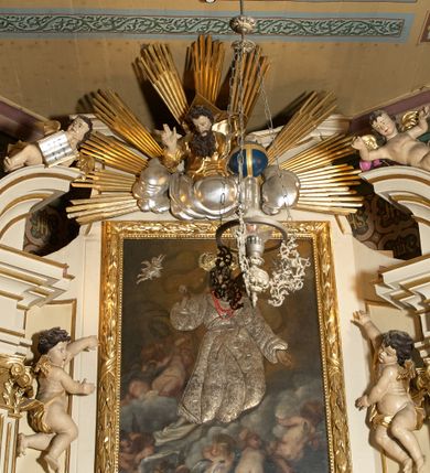 Zdjęcie nr 19: Ołtarz typu architektonicznego, jednokondygnacyjny, jednoosiowy, z bramkami i ze zwieńczeniem w formie glorii. Mensa prostopadłościenna, na ściance przedniej zdobiona rzędem płycin w kształcie stojącego prostokąta, zamkniętych łukiem nadwieszonym. W polu środkowej płyciny malowany krzyż grecki, w pozostałych gałązki białych lilii. Tabernakulum w formie prostopadłościennej skrzynki, z częścią środkową wysuniętą do przodu, zamknięte od góry profilowanym gzymsem w kształcie łuku nadwieszonego. Drzwiczki metalowe, pośrodku dekorowane płyciną w kształcie stojącego prostokąta, zamkniętego łukiem nadwieszonym, w polu kielich z hostią, kłosy zboża i kiście winogron. Nad tabernakulum tron wystawienia na tle promienistej glorii z monogramem IHS pośrodku, po bokach flankowany przez parę aniołków usadzonych na wolutach. Retabulum ustawione na wysokim cokole, ujęte parą zdwojonych, ukośnie ustawionych pilastrów podtrzymujących przerywane belkowanie, na którym usadzona para putt. Trzony pilastrów zdobione kanelowaniem, kapitele stylizowane, kompozytowe. Putto po lewej stronie z otwartą księgą, w której znajduje się napis: „Assu/pta / est / Maria / in / Caelum”. W polu głównym nastawy, na wysokości dwóch trzecich obraz z przedstawieniem Wniebowzięcia Najświętszej Marii Panny. Po bokach obrazu para rzeźbionych aniołków. W zwieńczeniu płaskorzeźba Boga Ojca na tle promienistej glorii. Drzwiczki bramek zdobione płyciną w kształcie stojącego prostokąta, zamkniętą od góry łukiem nadwieszonym. Zwieńczenie bramek zdobione festonem z liści wawrzynu, zakończone niskim cokołem, na którym ustawione rzeźby: po lewej św. Jana Chrzciciela, po prawej św. Kazimierza. Uszy ażurowe w postaci ornamentu rocaille'owego. Struktura ołtarza w kolorze beżowym, ornamentyka, detale i profilowania złocone.