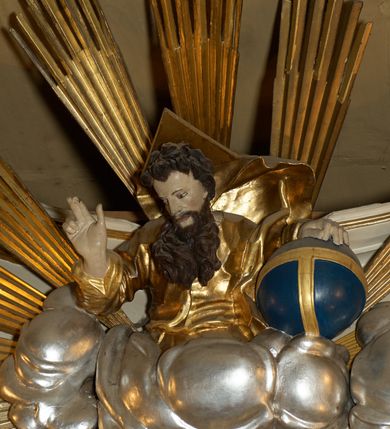 Zdjęcie nr 21: Ołtarz typu architektonicznego, jednokondygnacyjny, jednoosiowy, z bramkami i ze zwieńczeniem w formie glorii. Mensa prostopadłościenna, na ściance przedniej zdobiona rzędem płycin w kształcie stojącego prostokąta, zamkniętych łukiem nadwieszonym. W polu środkowej płyciny malowany krzyż grecki, w pozostałych gałązki białych lilii. Tabernakulum w formie prostopadłościennej skrzynki, z częścią środkową wysuniętą do przodu, zamknięte od góry profilowanym gzymsem w kształcie łuku nadwieszonego. Drzwiczki metalowe, pośrodku dekorowane płyciną w kształcie stojącego prostokąta, zamkniętego łukiem nadwieszonym, w polu kielich z hostią, kłosy zboża i kiście winogron. Nad tabernakulum tron wystawienia na tle promienistej glorii z monogramem IHS pośrodku, po bokach flankowany przez parę aniołków usadzonych na wolutach. Retabulum ustawione na wysokim cokole, ujęte parą zdwojonych, ukośnie ustawionych pilastrów podtrzymujących przerywane belkowanie, na którym usadzona para putt. Trzony pilastrów zdobione kanelowaniem, kapitele stylizowane, kompozytowe. Putto po lewej stronie z otwartą księgą, w której znajduje się napis: „Assu/pta / est / Maria / in / Caelum”. W polu głównym nastawy, na wysokości dwóch trzecich obraz z przedstawieniem Wniebowzięcia Najświętszej Marii Panny. Po bokach obrazu para rzeźbionych aniołków. W zwieńczeniu płaskorzeźba Boga Ojca na tle promienistej glorii. Drzwiczki bramek zdobione płyciną w kształcie stojącego prostokąta, zamkniętą od góry łukiem nadwieszonym. Zwieńczenie bramek zdobione festonem z liści wawrzynu, zakończone niskim cokołem, na którym ustawione rzeźby: po lewej św. Jana Chrzciciela, po prawej św. Kazimierza. Uszy ażurowe w postaci ornamentu rocaille&#039;owego. Struktura ołtarza w kolorze beżowym, ornamentyka, detale i profilowania złocone.