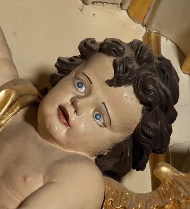 Zdjęcie nr 6: Ołtarz typu architektonicznego, jednokondygnacyjny, jednoosiowy, z bramkami i ze zwieńczeniem w formie glorii. Mensa prostopadłościenna, na ściance przedniej zdobiona rzędem płycin w kształcie stojącego prostokąta, zamkniętych łukiem nadwieszonym. W polu środkowej płyciny malowany krzyż grecki, w pozostałych gałązki białych lilii. Tabernakulum w formie prostopadłościennej skrzynki, z częścią środkową wysuniętą do przodu, zamknięte od góry profilowanym gzymsem w kształcie łuku nadwieszonego. Drzwiczki metalowe, pośrodku dekorowane płyciną w kształcie stojącego prostokąta, zamkniętego łukiem nadwieszonym, w polu kielich z hostią, kłosy zboża i kiście winogron. Nad tabernakulum tron wystawienia na tle promienistej glorii z monogramem IHS pośrodku, po bokach flankowany przez parę aniołków usadzonych na wolutach. Retabulum ustawione na wysokim cokole, ujęte parą zdwojonych, ukośnie ustawionych pilastrów podtrzymujących przerywane belkowanie, na którym usadzona para putt. Trzony pilastrów zdobione kanelowaniem, kapitele stylizowane, kompozytowe. Putto po lewej stronie z otwartą księgą, w której znajduje się napis: „Assu/pta / est / Maria / in / Caelum”. W polu głównym nastawy, na wysokości dwóch trzecich obraz z przedstawieniem Wniebowzięcia Najświętszej Marii Panny. Po bokach obrazu para rzeźbionych aniołków. W zwieńczeniu płaskorzeźba Boga Ojca na tle promienistej glorii. Drzwiczki bramek zdobione płyciną w kształcie stojącego prostokąta, zamkniętą od góry łukiem nadwieszonym. Zwieńczenie bramek zdobione festonem z liści wawrzynu, zakończone niskim cokołem, na którym ustawione rzeźby: po lewej św. Jana Chrzciciela, po prawej św. Kazimierza. Uszy ażurowe w postaci ornamentu rocaille'owego. Struktura ołtarza w kolorze beżowym, ornamentyka, detale i profilowania złocone.