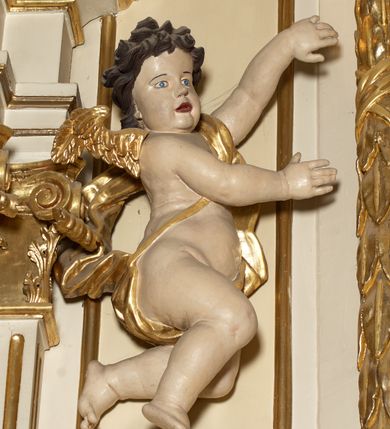 Zdjęcie nr 7: Ołtarz typu architektonicznego, jednokondygnacyjny, jednoosiowy, z bramkami i ze zwieńczeniem w formie glorii. Mensa prostopadłościenna, na ściance przedniej zdobiona rzędem płycin w kształcie stojącego prostokąta, zamkniętych łukiem nadwieszonym. W polu środkowej płyciny malowany krzyż grecki, w pozostałych gałązki białych lilii. Tabernakulum w formie prostopadłościennej skrzynki, z częścią środkową wysuniętą do przodu, zamknięte od góry profilowanym gzymsem w kształcie łuku nadwieszonego. Drzwiczki metalowe, pośrodku dekorowane płyciną w kształcie stojącego prostokąta, zamkniętego łukiem nadwieszonym, w polu kielich z hostią, kłosy zboża i kiście winogron. Nad tabernakulum tron wystawienia na tle promienistej glorii z monogramem IHS pośrodku, po bokach flankowany przez parę aniołków usadzonych na wolutach. Retabulum ustawione na wysokim cokole, ujęte parą zdwojonych, ukośnie ustawionych pilastrów podtrzymujących przerywane belkowanie, na którym usadzona para putt. Trzony pilastrów zdobione kanelowaniem, kapitele stylizowane, kompozytowe. Putto po lewej stronie z otwartą księgą, w której znajduje się napis: „Assu/pta / est / Maria / in / Caelum”. W polu głównym nastawy, na wysokości dwóch trzecich obraz z przedstawieniem Wniebowzięcia Najświętszej Marii Panny. Po bokach obrazu para rzeźbionych aniołków. W zwieńczeniu płaskorzeźba Boga Ojca na tle promienistej glorii. Drzwiczki bramek zdobione płyciną w kształcie stojącego prostokąta, zamkniętą od góry łukiem nadwieszonym. Zwieńczenie bramek zdobione festonem z liści wawrzynu, zakończone niskim cokołem, na którym ustawione rzeźby: po lewej św. Jana Chrzciciela, po prawej św. Kazimierza. Uszy ażurowe w postaci ornamentu rocaille'owego. Struktura ołtarza w kolorze beżowym, ornamentyka, detale i profilowania złocone.