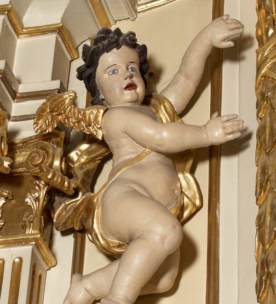 Zdjęcie nr 8: Ołtarz typu architektonicznego, jednokondygnacyjny, jednoosiowy, z bramkami i ze zwieńczeniem w formie glorii. Mensa prostopadłościenna, na ściance przedniej zdobiona rzędem płycin w kształcie stojącego prostokąta, zamkniętych łukiem nadwieszonym. W polu środkowej płyciny malowany krzyż grecki, w pozostałych gałązki białych lilii. Tabernakulum w formie prostopadłościennej skrzynki, z częścią środkową wysuniętą do przodu, zamknięte od góry profilowanym gzymsem w kształcie łuku nadwieszonego. Drzwiczki metalowe, pośrodku dekorowane płyciną w kształcie stojącego prostokąta, zamkniętego łukiem nadwieszonym, w polu kielich z hostią, kłosy zboża i kiście winogron. Nad tabernakulum tron wystawienia na tle promienistej glorii z monogramem IHS pośrodku, po bokach flankowany przez parę aniołków usadzonych na wolutach. Retabulum ustawione na wysokim cokole, ujęte parą zdwojonych, ukośnie ustawionych pilastrów podtrzymujących przerywane belkowanie, na którym usadzona para putt. Trzony pilastrów zdobione kanelowaniem, kapitele stylizowane, kompozytowe. Putto po lewej stronie z otwartą księgą, w której znajduje się napis: „Assu/pta / est / Maria / in / Caelum”. W polu głównym nastawy, na wysokości dwóch trzecich obraz z przedstawieniem Wniebowzięcia Najświętszej Marii Panny. Po bokach obrazu para rzeźbionych aniołków. W zwieńczeniu płaskorzeźba Boga Ojca na tle promienistej glorii. Drzwiczki bramek zdobione płyciną w kształcie stojącego prostokąta, zamkniętą od góry łukiem nadwieszonym. Zwieńczenie bramek zdobione festonem z liści wawrzynu, zakończone niskim cokołem, na którym ustawione rzeźby: po lewej św. Jana Chrzciciela, po prawej św. Kazimierza. Uszy ażurowe w postaci ornamentu rocaille'owego. Struktura ołtarza w kolorze beżowym, ornamentyka, detale i profilowania złocone.